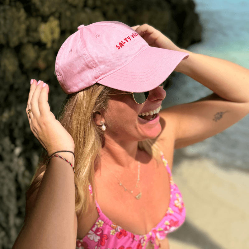 Woman at the beach wearing pink dad cap with Salty Vibes from Cap Society